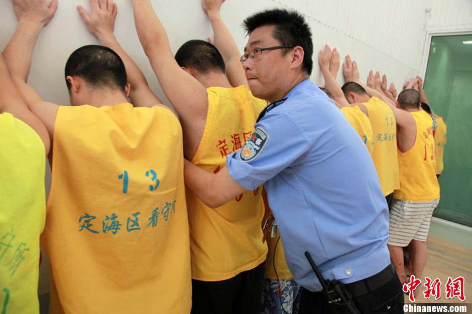 2013年7月9日，浙江省舟山市定海区看守所搬迁。300余名在押人员安全转移至距离城区10公里外的新所，330名武警、公安干警全副武装押解。图为公安干警检查在押人员的行李。琳红 摄 图片来源：CFP视觉中国