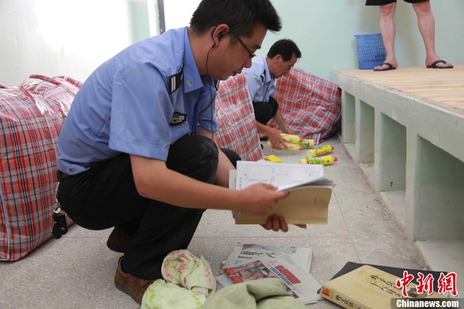 2013年7月9日，浙江省舟山市定海区看守所搬迁。300余名在押人员安全转移至距离城区10公里外的新所，330名武警、公安干警全副武装押解。图为公安干警检查在押人员的行李。琳红 摄 图片来源：CFP视觉中国