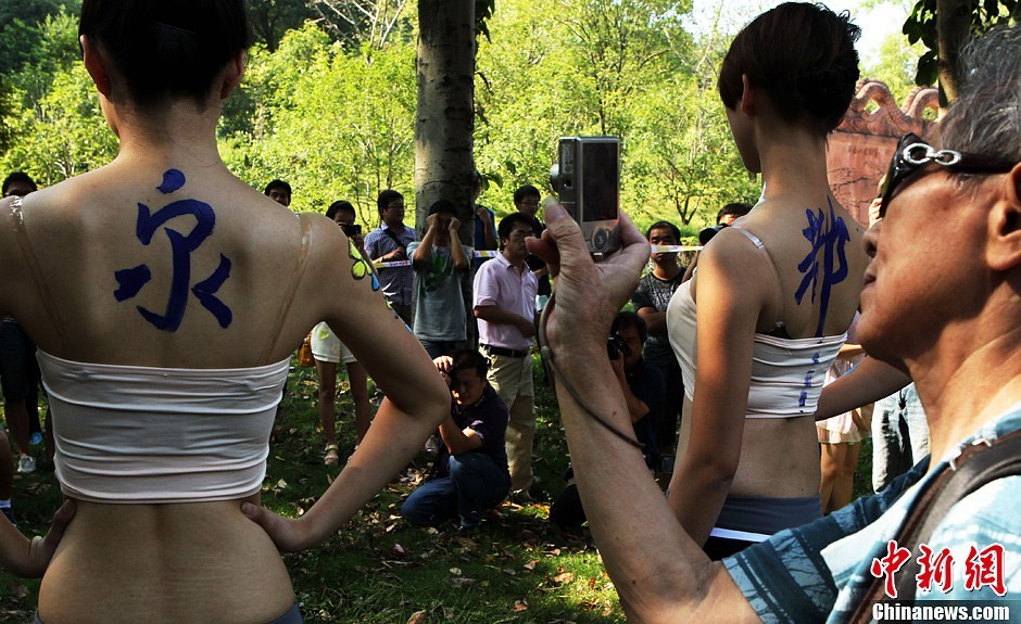 9月20日，2013国际旅游小姐菁英赛在湖北咸宁举行赛事活动，选自中国各地的40位佳丽来到咸宁市人民广场进行人体彩绘表演，吸引众多摄影爱好者及市民观赏。图为游客拍照。中新社发 钱兴强 摄