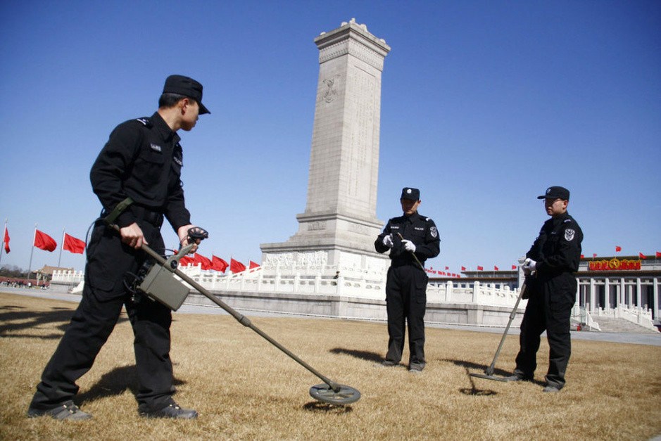 天安门广场，安保人员用金属探测器检查地面。
