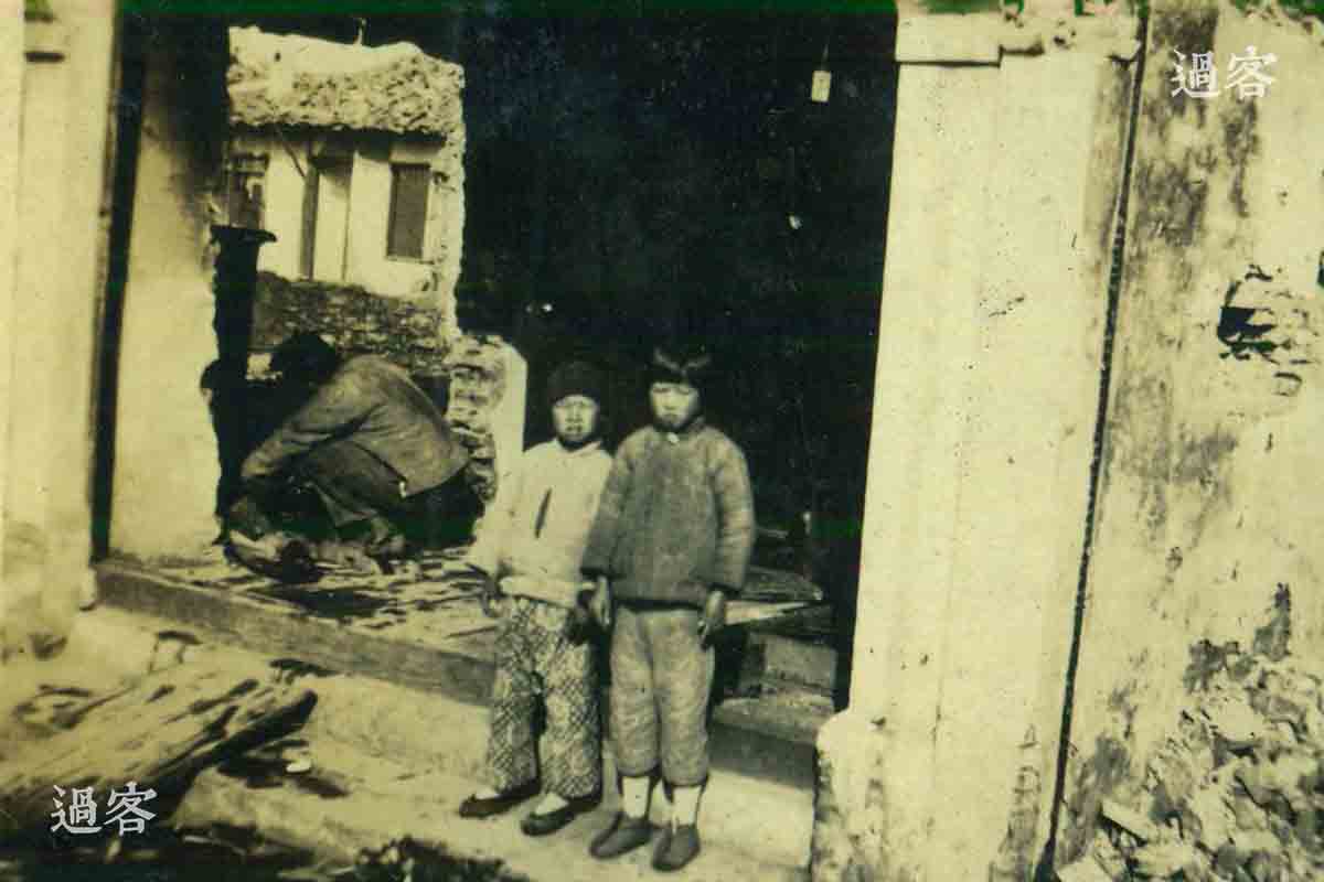 图为站在被战火摧毁的家宅门口的孩童。（来源：网易新媒体）