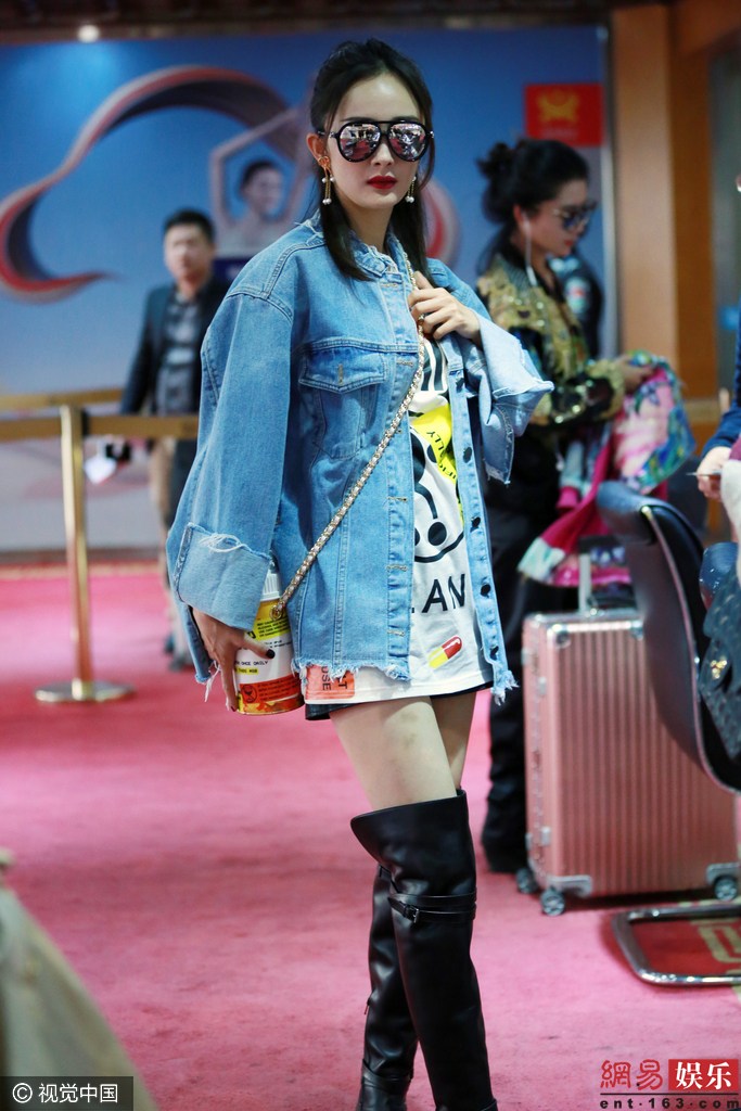 网易娱乐10月14日报道（图文/视觉中国）13日，杨幂现身机场，赴长沙参加金鹰电视艺术节。她梳减龄丸子头，身穿牛仔装搭配卡通T恤，脚踩长筒靴时尚摩登秀大白腿，背着药瓶包俏皮可爱。（来源：视觉中国）
