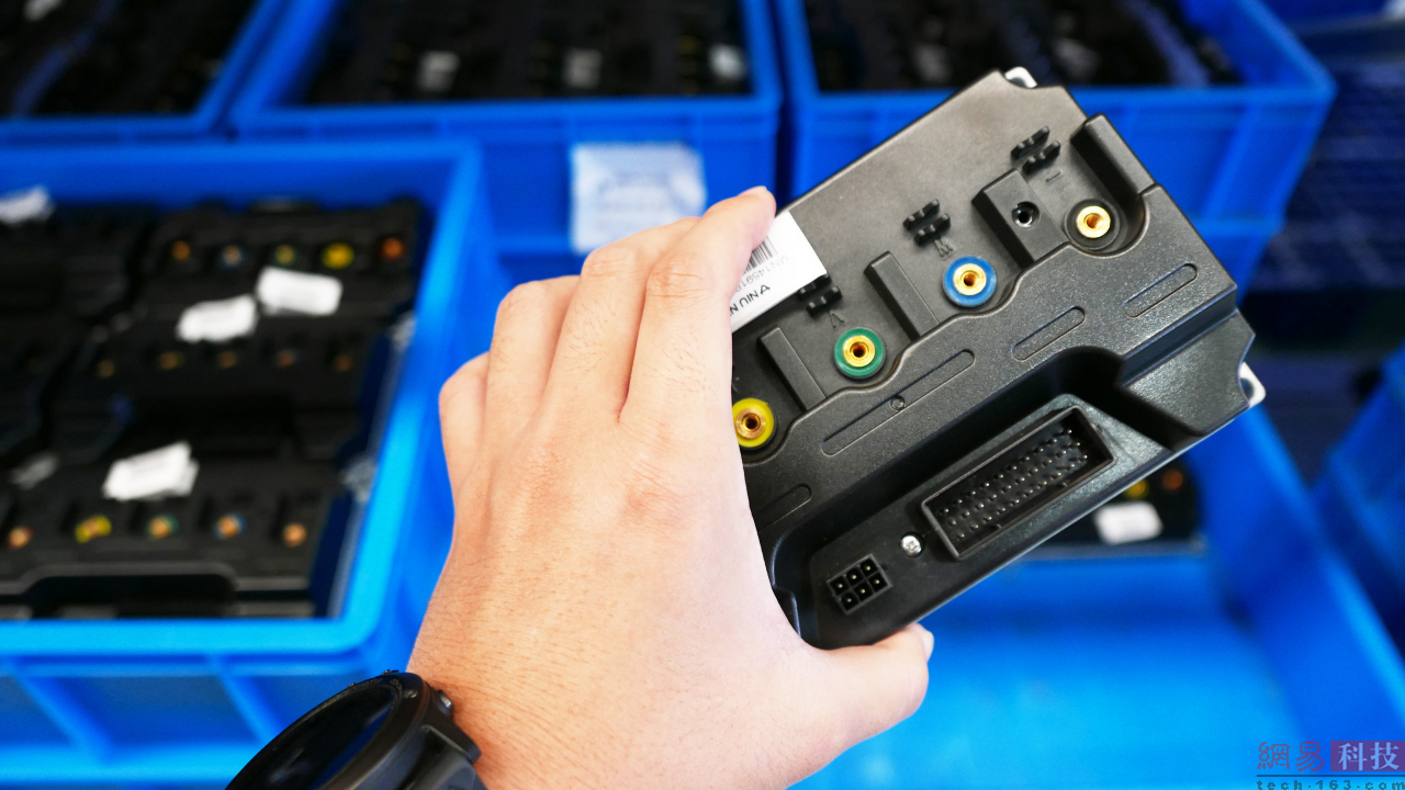 随手拿起小牛电动车待组装的部件。（来源：网易科技）